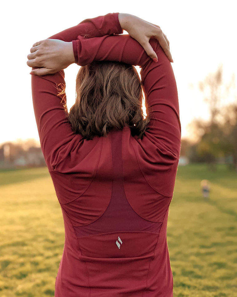 Woman doing a post workout stretch in a red long-sleeve shirt
