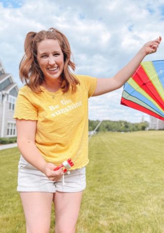 Girl with a yellow shirt flies a kite to pay it forward