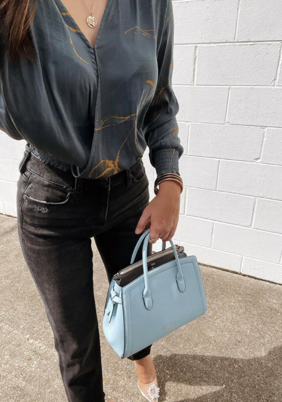 woman in a wrap top with a blue bag featuring some of the best clothes for an hourglass body shape - @chloeperr