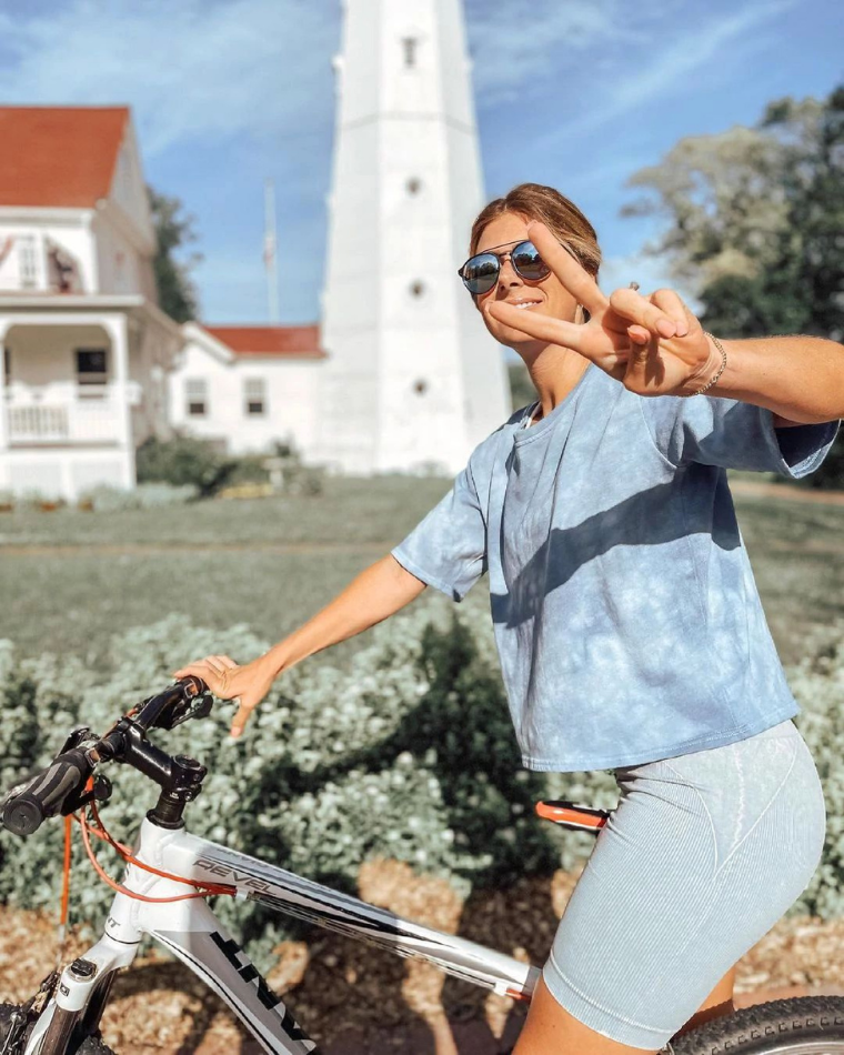 woman riding a bike and giving a peace sign - ways to love your body @samanthaporter__