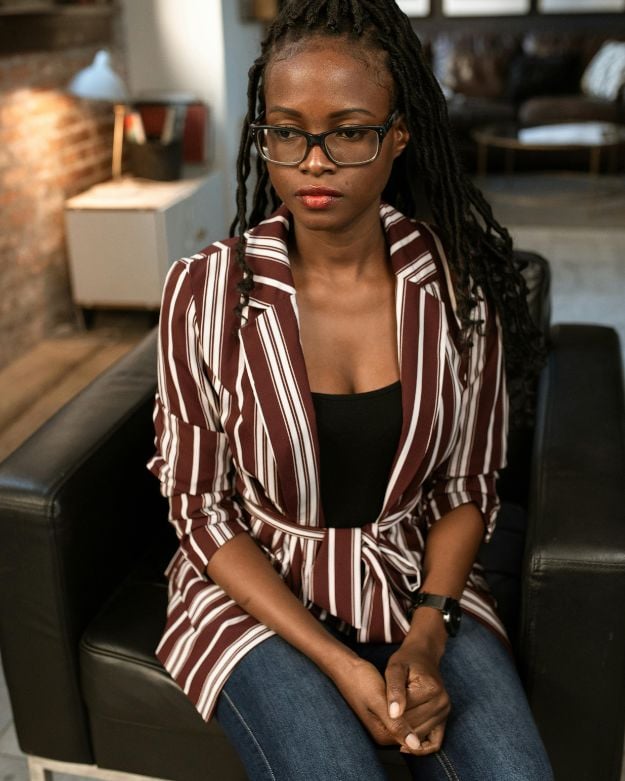 A woman wearing a striped blazer with jeans for an office-friendly look.