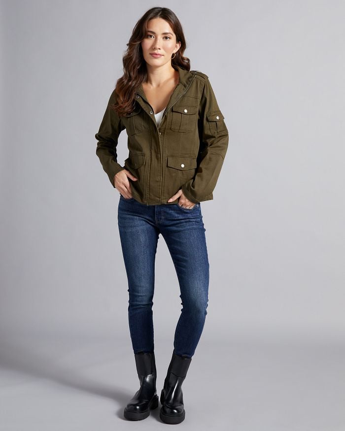 Brunette wearing dark wash skinny jeans and an olive utility jacket.