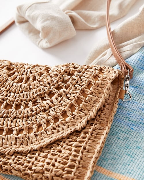 An up-close photo showing the intricate detail on a woven crossbody bag. Shows how to style spring dresses with a textured bag.