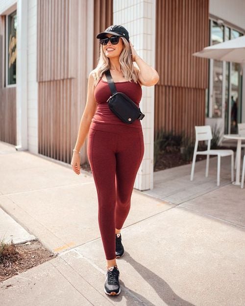 A Wantable influencer wearing an adorable matching red workout set with a black sling bag, hat, and sneakers. 