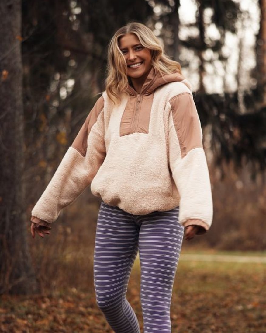 A Wantable influencer in a cozy fleece pullover and striped leggings – the perfect airplane look for any trip. 