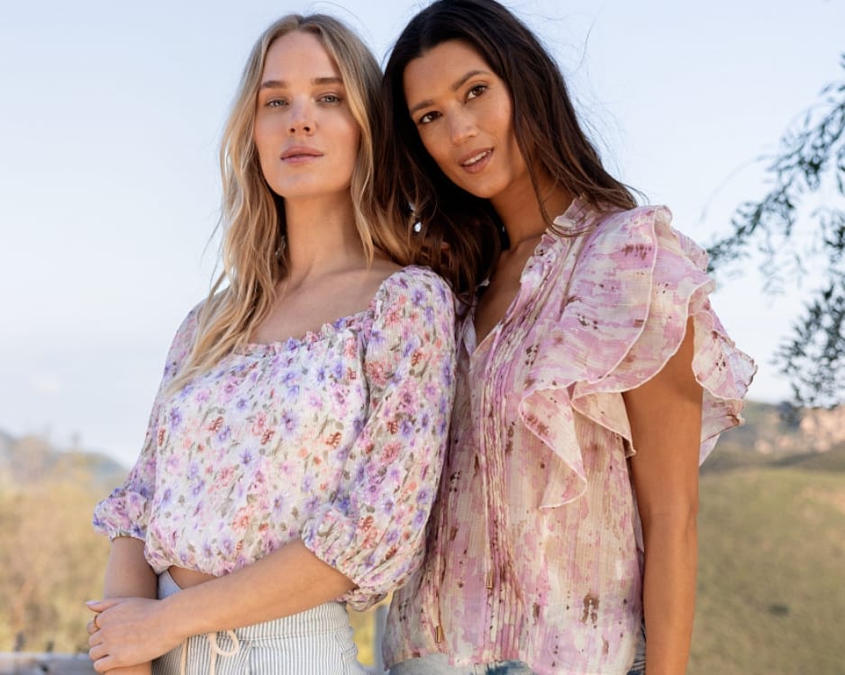 Two women wearing April Theory-inspired chiffon floral tops with puff sleeves and ruffles outdoors during spring.