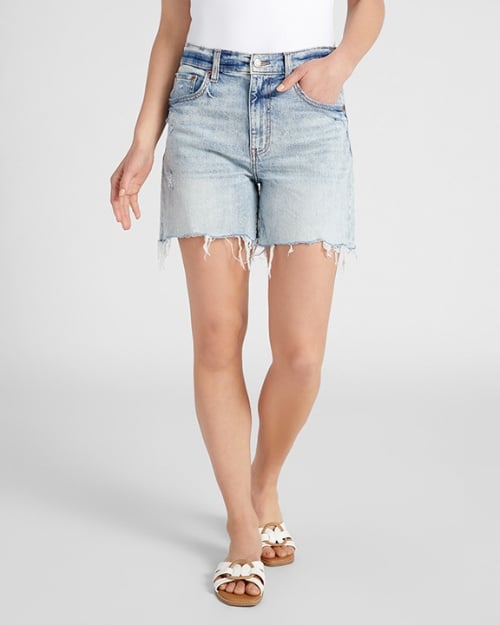 A photo of a Wantable model wearing a pair of high-waisted shorts and white sandals. One of her hands is in her pocket. 