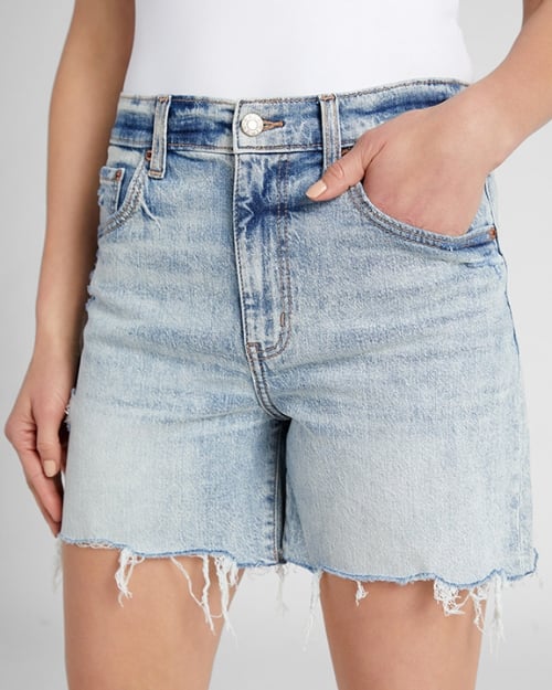 A close-up photo of a Wantable model wearing a pair of denim boyfriend shorts. One of her hands is in her pocket. 