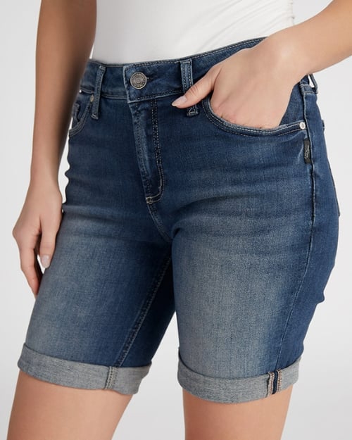 An up-close photo of a Wantable model wearing a pair of denim Bermuda shorts. One of her hands is in her pocket. 