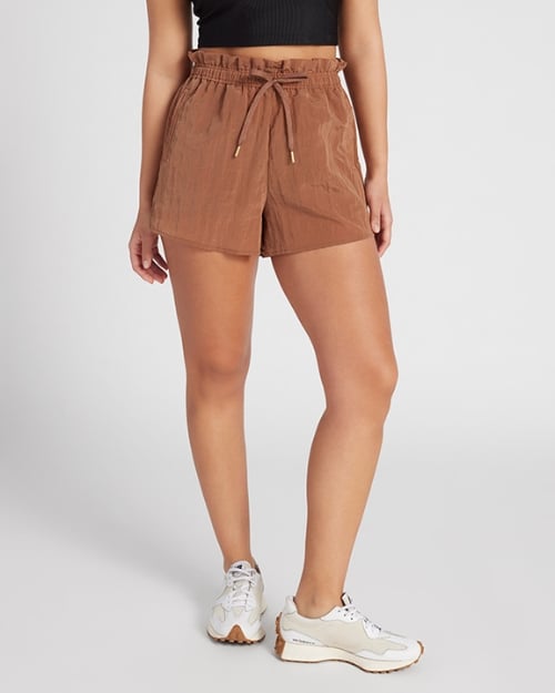 A photo of a Wantable model wearing a pair of nylon paperbag shorts and tennis shoes. 