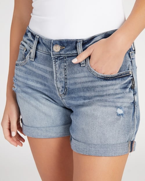 An up-close photo of a Wantable model wearing a pair of denim boyfriend shorts. One of her hands is in her front pocket. 