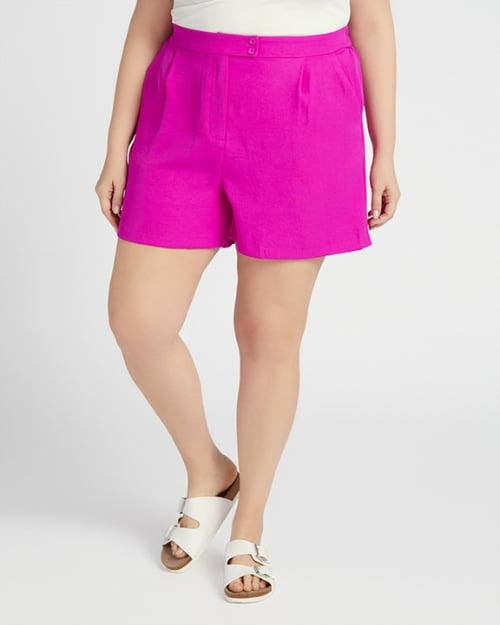 A photo of a Wantable model wearing bright pink tailored shorts and white sandals.