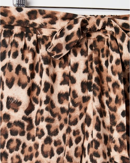 An up-close photo of the tied belt on a pair of leopard print shorts with a loose, flowy fit. 